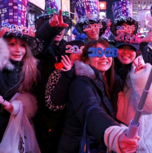 Люди в святкових капелюхах та окулярах з написом 2026 після падіння кулі на Таймс-Сквер, Нью-Йорк, США